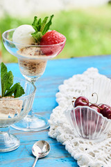 A mix of strawberry, vanilla and caramel ice cream served in a glass beaker on a wooden table