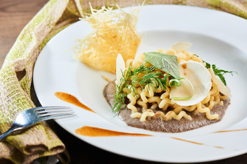 Dinner pasta fusilli with mushroom sauce served on a white plate