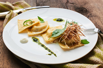Ravioli with duck and cream sauce, served on a white plate