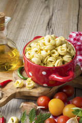 Homemade pasta. Traditional Italian tortellini in a red ceramic saucepan