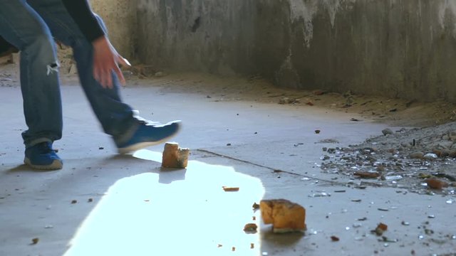 A young man taking a brick and throw it through the window. Slowly