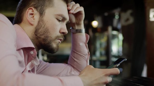 sad young man with cell phone in a bar