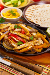 Chicken Fajitas with Grilled Onions and Bell Peppers serve with Tortillas. Selective focus.