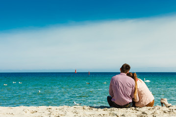 couple sitting on beach rear view