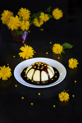 Panacotta - italian dessert with yellow flowers on dark background