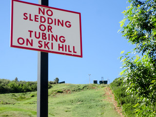 No sledding or tubing on ski hill sign in the summertime