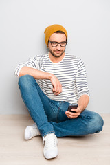 Portrait of hipster man in cap and glasses typing sms