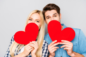 Portrait of man in woman hiding faces behind paper hearts