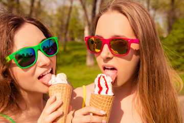 Portrait of two sexy girls in glasses licking ice cream
