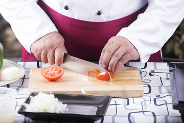Obraz na płótnie Canvas Chef cutting Tomato with knife before cooking
