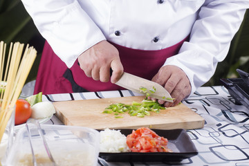 Chef chopping green bell pepper with knife before cooking