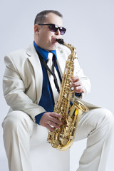 Fototapeta na wymiar Music Ideas and Concepts. Handsome and Expressive Caucasian Musician with Saxophone Against White