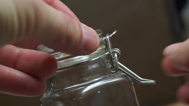 Close up shot of a reusable sealing glass preserve storage jar being closed by an anonymous person.