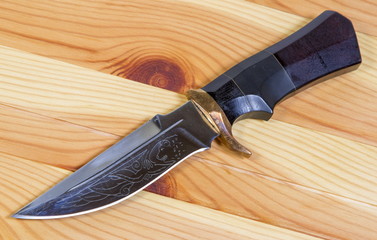 Beautiful hunting knife against wooden background