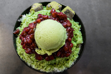 Green tea matcha ice cream scoop in bowl on a grey stone background Copy space.Ice cream with beans in the Korean style