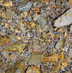 natural stones in the river and the sun glare on the water