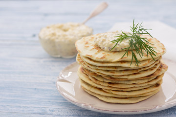 Flat bread with egg dip and dill on a blue wooden background, selective focus
