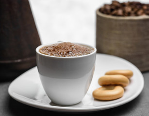 Cup of coffee, a Turk and grains on gray background