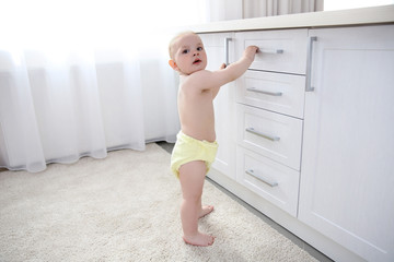 Baby boy playing with drawers in the room