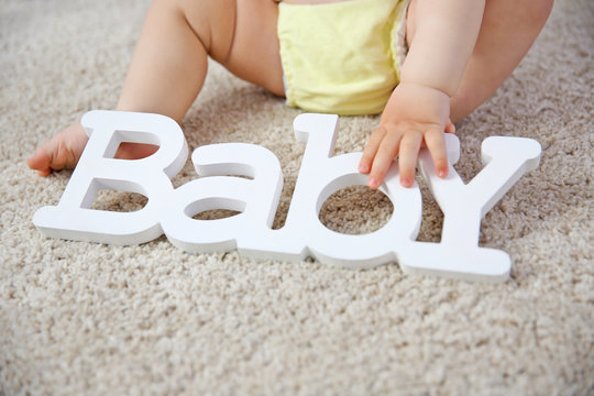 Baby legs and decorative word on the floor