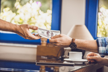 man sitting in the cafe gives money to another man