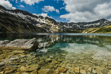 Mountains reflection in alpine lake at sunny day