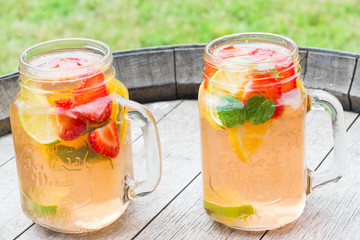 Homemade strawberry lemonade with fresh fruits, served outside.