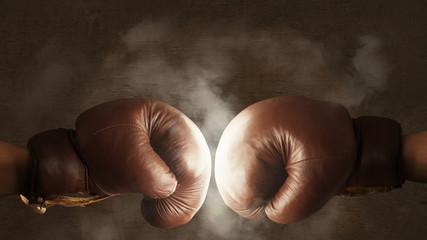 Two old brown boxing gloves hit together