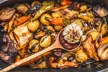 Cooked rabbit stew with  forest mushrooms , roasted vegetables of season and rustic wooden spoon, top view, close up
