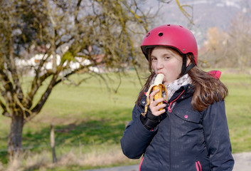 preteen with roller skate helmet, eat banana
