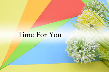 concept image,quote " time for you" on yellow,orange, red, green and blue color paper with blossom artificial flower background