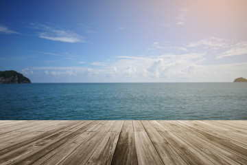 Wooden board empty in front of blurred sea and blue sky with cloud ,can be used for display or present your product or food. summer season. sunlight effect on right top corner