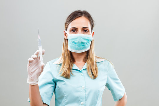 Nurse with protective mask  holding injection.