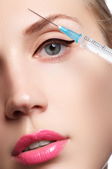 Portrait of young woman getting cosmetic injection. Closeup of beautiful woman gets injection in her face. Filler injections. Lip augmentation. Beautiful perfect lips

