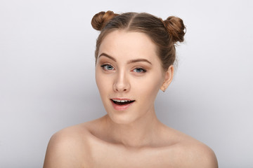 Portrait of a young woman with funny hairstyle and bare shoulders act the ape against white studio background