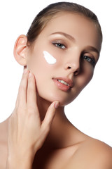 Beautiful face of young woman with cosmetic cream on a cheek