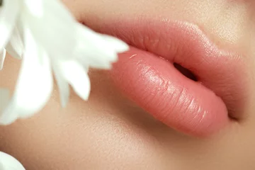 Fotobehang Lips with flower. Close-up beautiful female lips with bright lips © looking2thesky