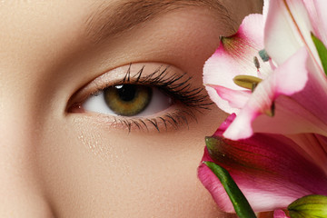 Fototapeta premium Gorgeous young model, beautiful woman eye with fresh pink flower