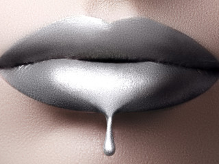 Close-up of liquid silver woman lips with glittering silver