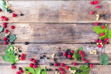 Raspberries and currants on a wooden background with copy space 