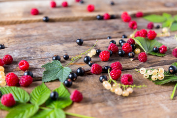 Fototapeta na wymiar Raspberries and currants on a wooden background