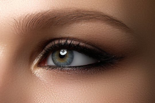 Elegance close-up of female eye with classic dark brown smoky make-up