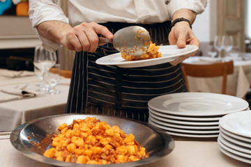Chef is putting gnocci with meat in plates