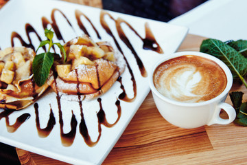 pancakes with chocolate and fruit and coffee on wooden background. Beautiful restaurant serving the dessert