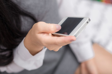 Cute asian woman using her cellphone in living room