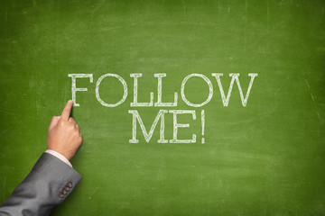 Follow Me text on blackboard with businessman hand pointing