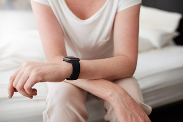 Woman sitting on bed wearing a wrist watch