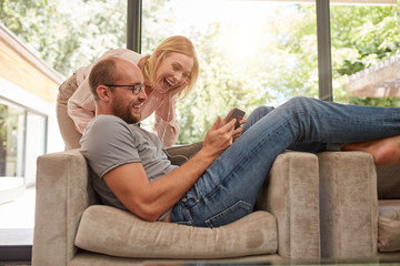 Laughing couple at home using digital tablet