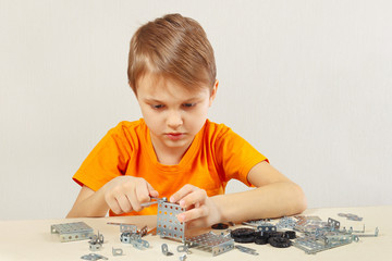 Little cute boy plays with mechanical constructor at the table