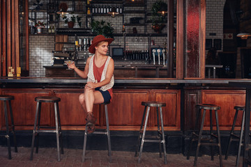 Fototapeta na wymiar Stylish young female sitting at a cafe with drink